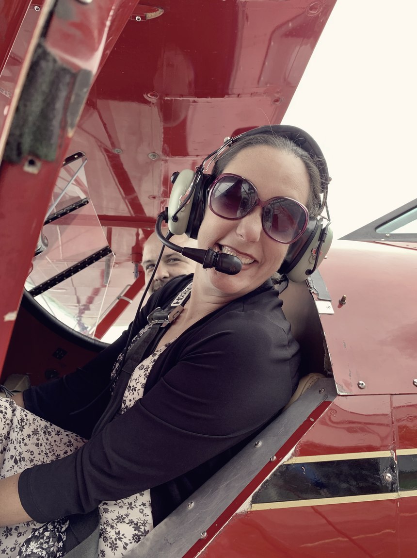 Meagan Crawford in the cockpit of a red biplane, wearing a headset.